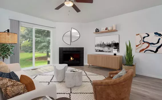 Modern living room with white sofa, brown armchair, black fireplace, and sliding glass door to a green yard.