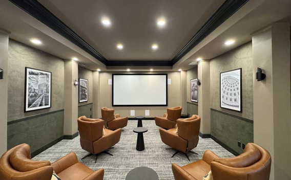 Stylish private screening room with six brown leather chairs facing a large projection screen and framed artwork.