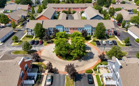 Aerial photograph of a residential community featuring colorful apartment buildings surrounding a circular green space.