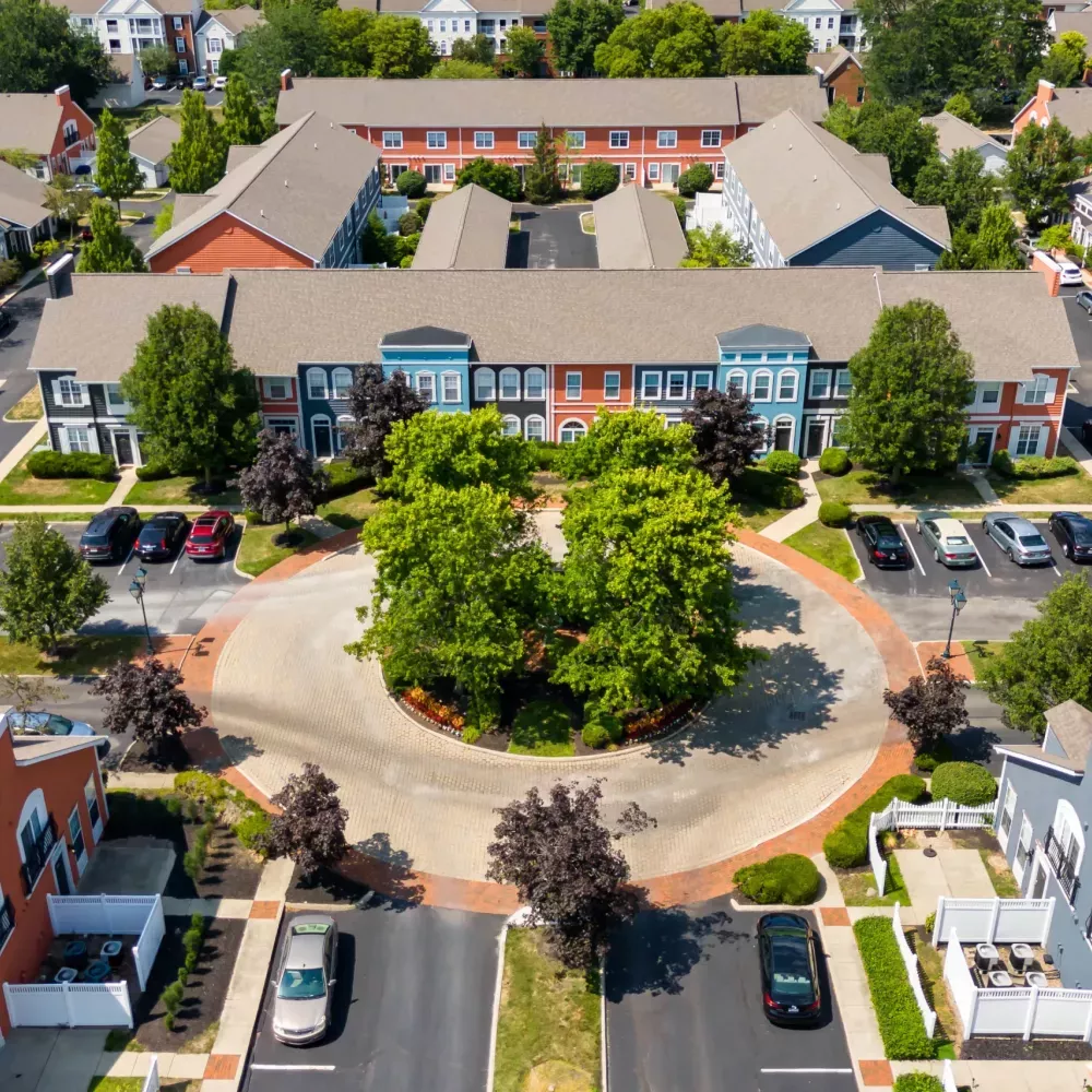Aerial photograph of a residential community featuring colorful apartment buildings surrounding a circular green space.